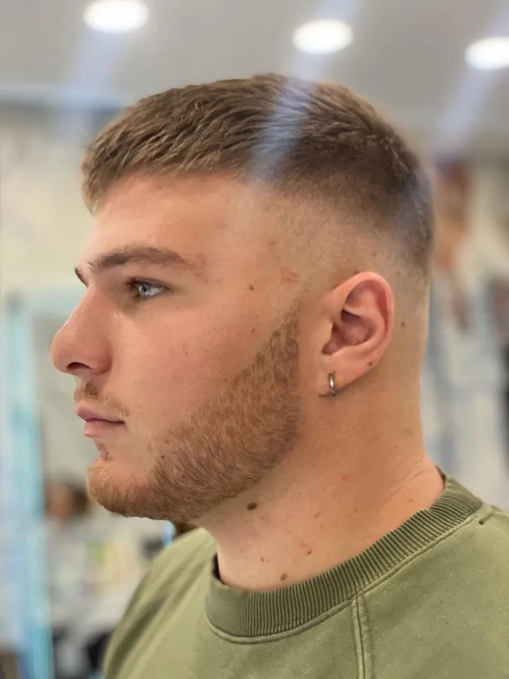 Ragazzo biondo con un crop corto e la sfumatura, di profilo