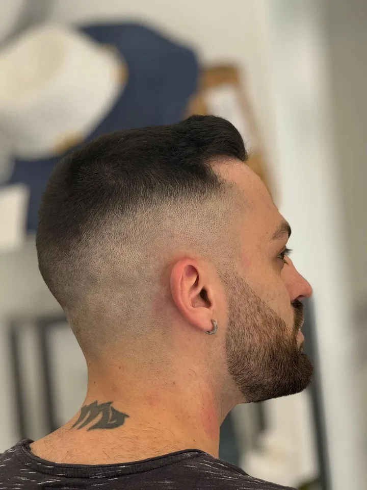 Uomo di nuca e di profilo, con la sfumatura alta e la barba