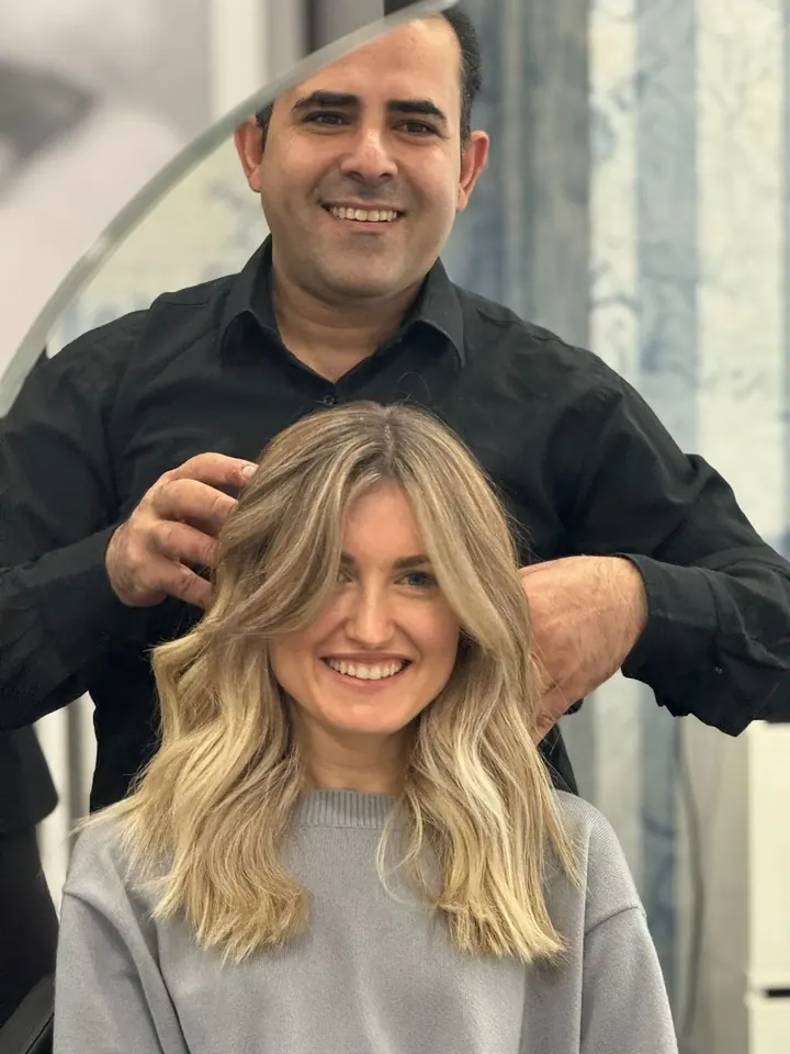 Il parrucchiere sistema le onde bionde di una cliente sorridente